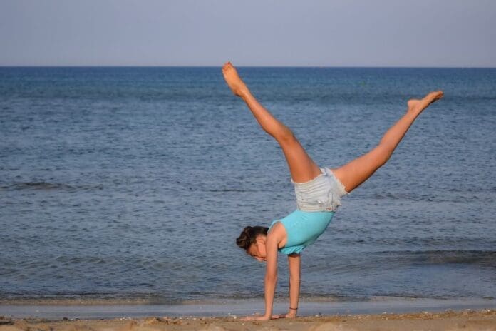 A Fit and Healthy Lifestyle Woman doing a cartwheel on the beach
